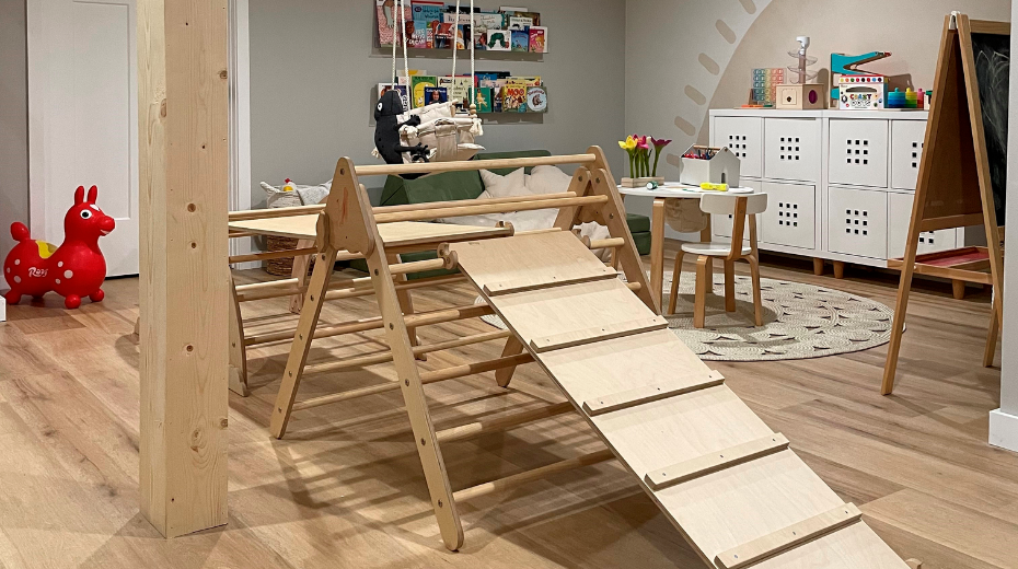 Basement playroom with a wooden play structure, toys, books, and storage